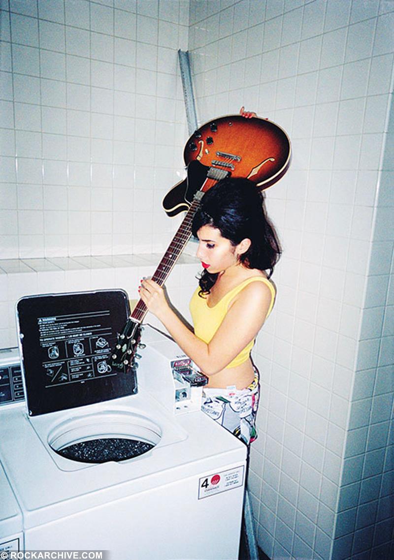 Amy Winehouse stood with guitar by washing machine in 2003 photographed by Charles Moriarty