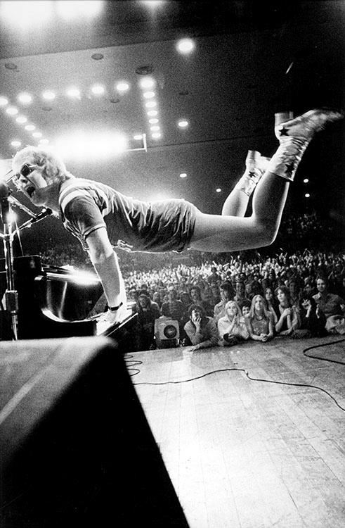 Elton John jumping in the air whilst playing the piano in Los Angeles in 1970