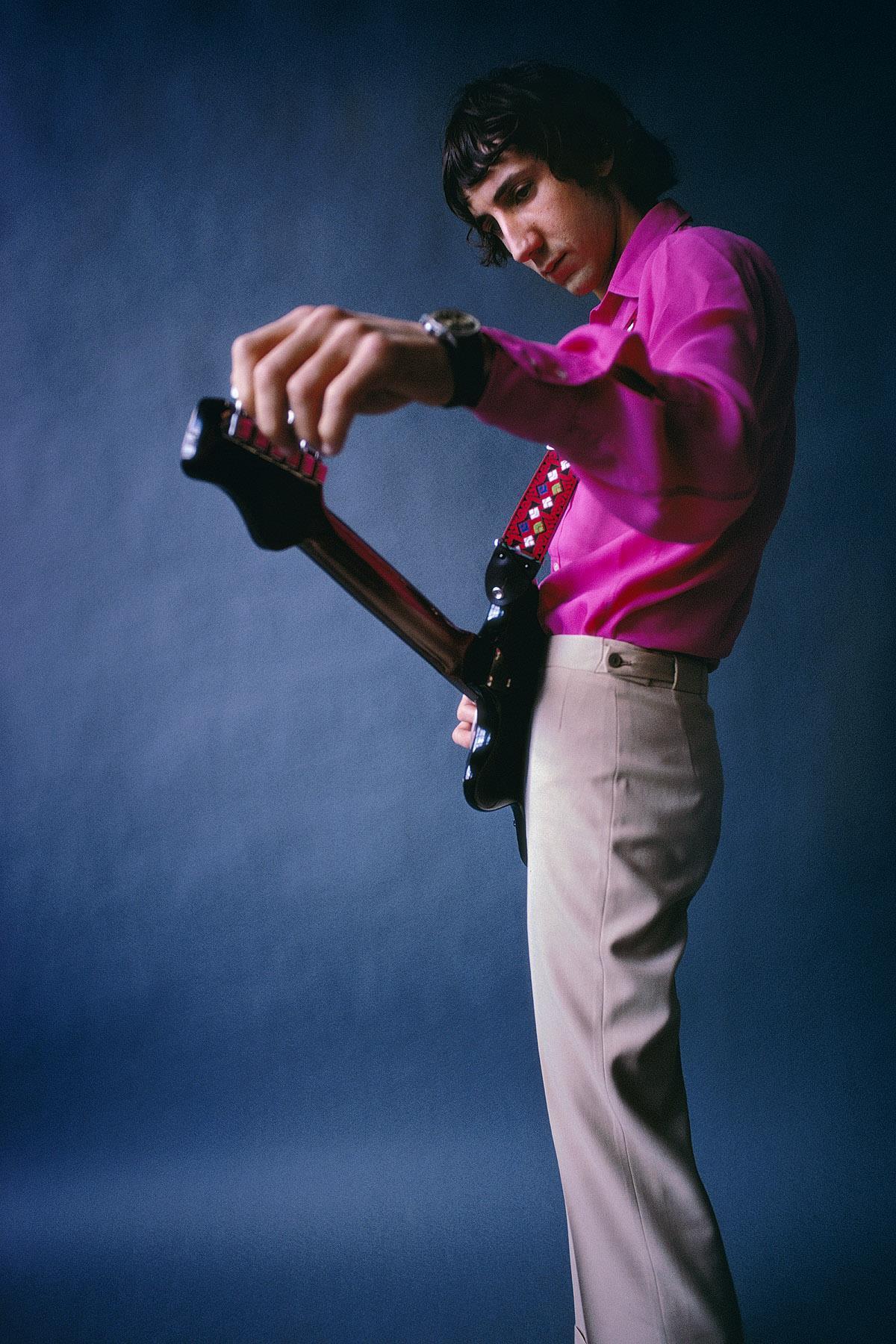 Pete Townshend wearing a pink shirt and holding his guitar in 1968.