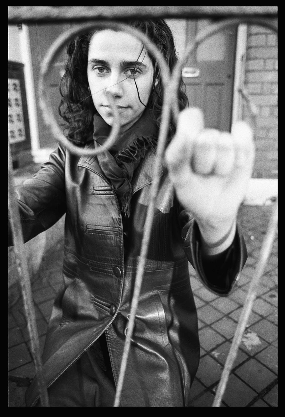 A limited edition print of PJ Harvey shot through railings she is holding onto.