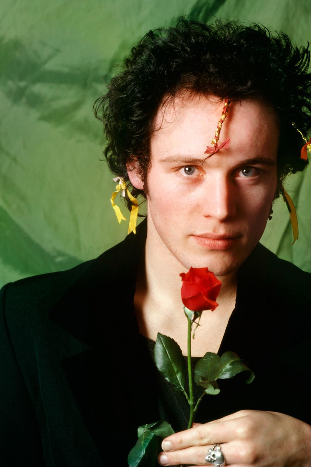A Rockarchive limited edition colour print of Adam Ant holding a single red rose set against a green background.