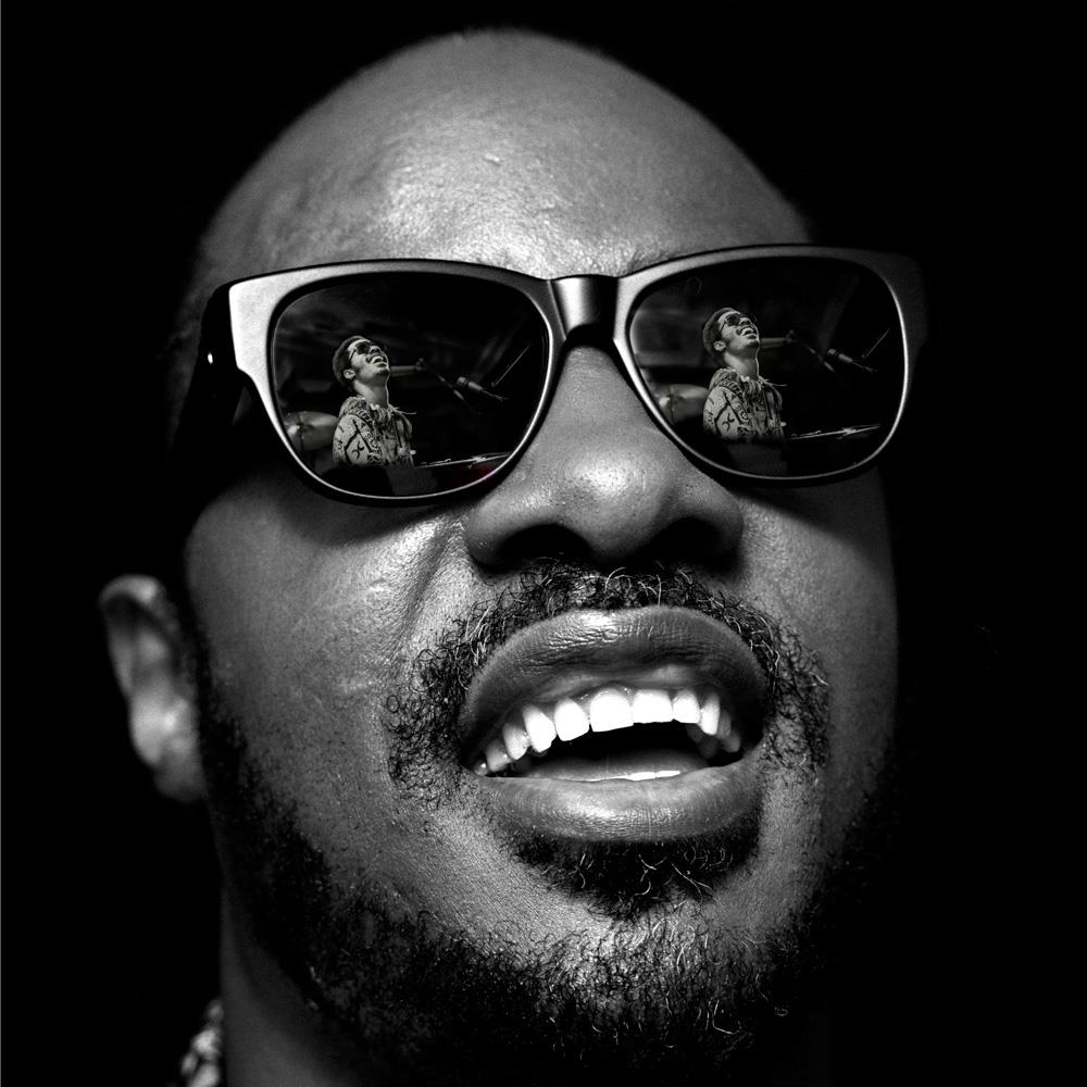 A limited edition print of Stevie Wonder smiling and wearing glasses showing a reflection of his younger self