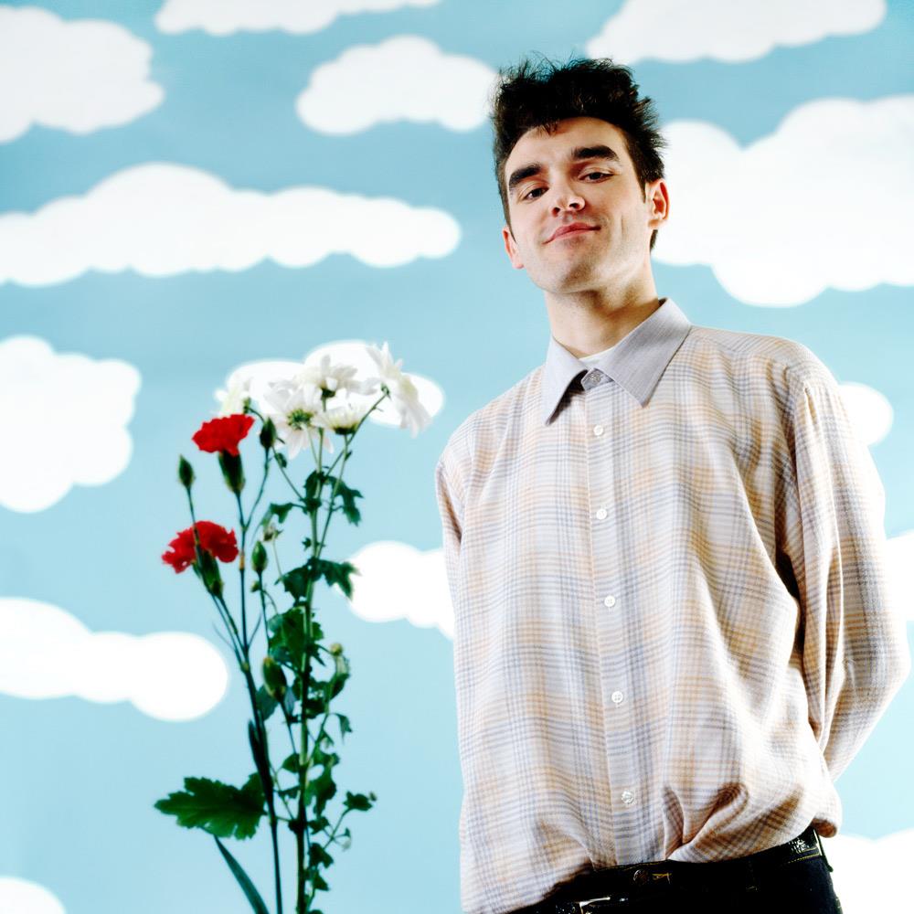 A limited edition print of Morrissey stood by flowers against a cartoon sky background.