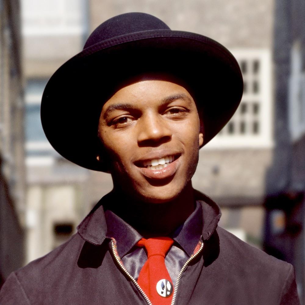 A limited edition colour print of Ranking Roger from The Beat standing in London Bridge wearing a hat and red tie.