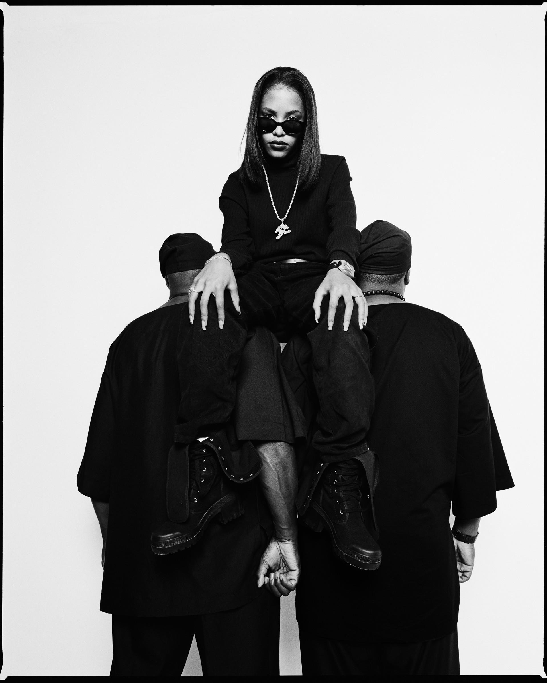 A limited edition print of Aaliyah sat on the shoulders of two men.