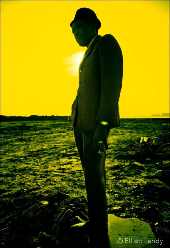 A limited edition colour print of John Lee Hooker stood against a yellow sky background.