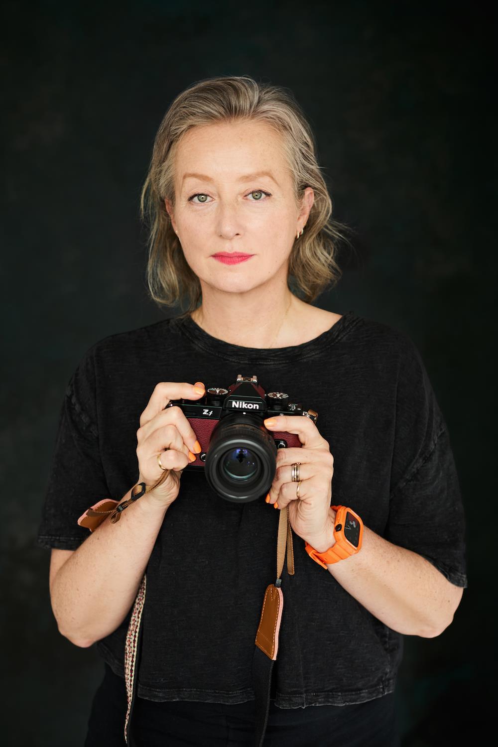 Portrait of photographer Scarlet Page holding a camera.