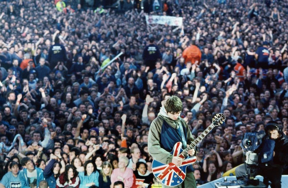 A limited edition colour print of Noel Gallagher pl,aying guitar when Oasis performed at Maine Rpad in 1996.