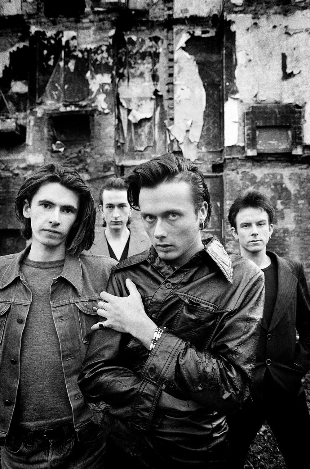 A limited edition print of a group shot of Suede stood near a wall.