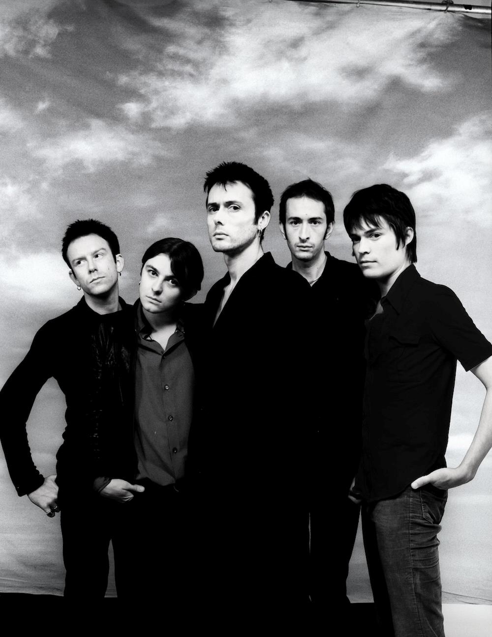 A limited edition print of a grouo shot of Suede all wearing black shirts.