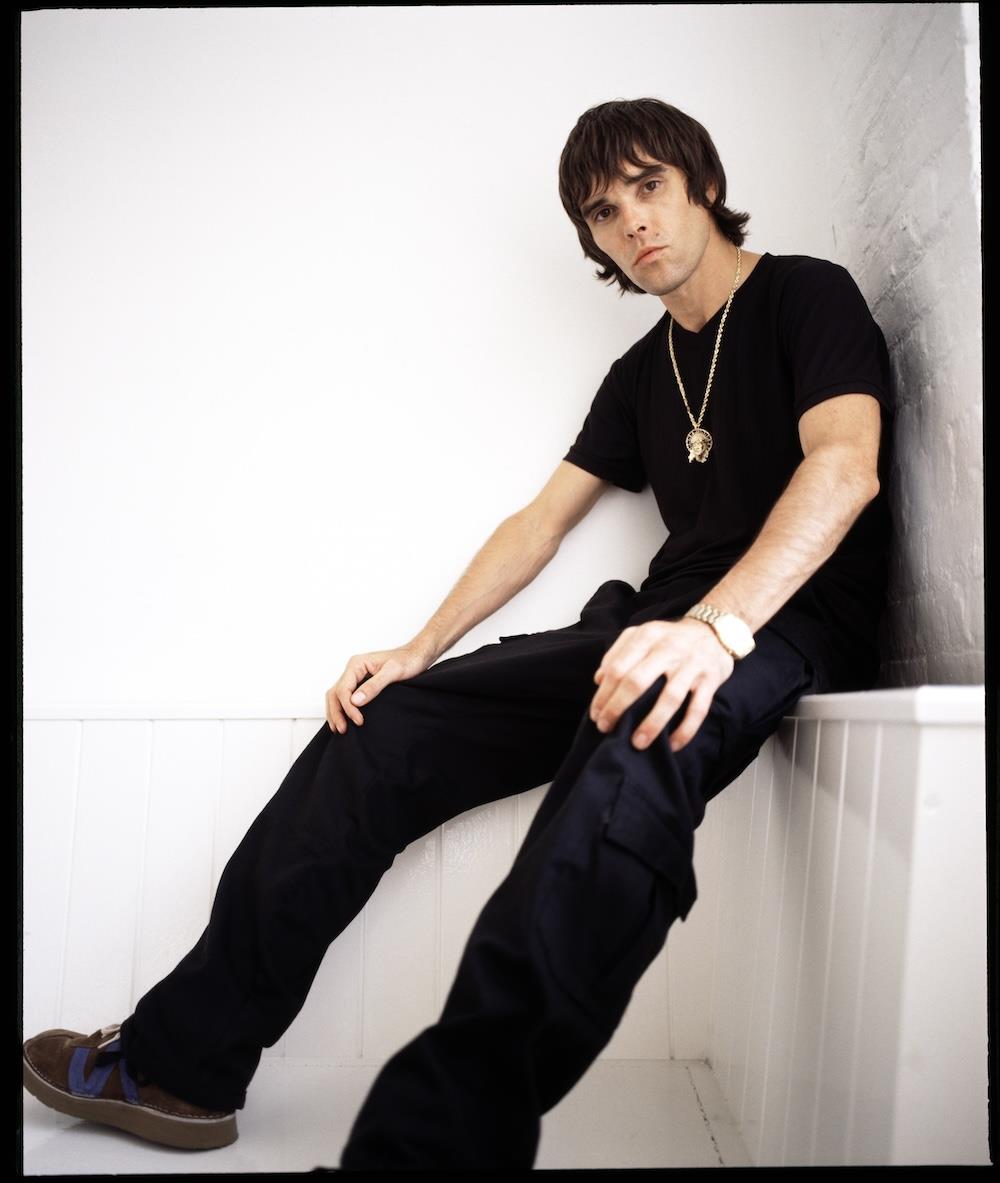A limited edition colour print of Ian Brown, Stone Roses sat down in a white shelf.