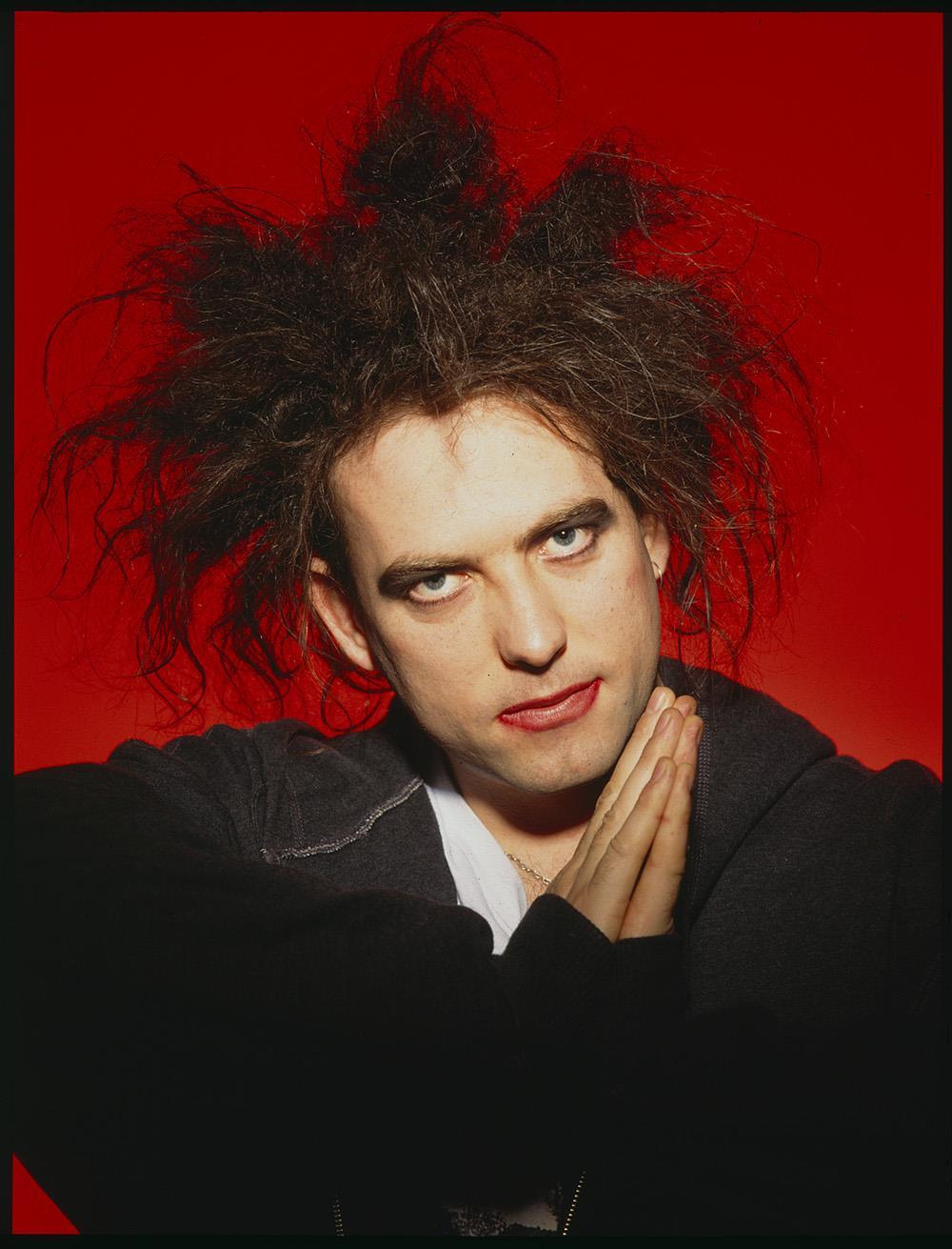 A fine art print of Robert Smith of The Cure photographed against a red background.