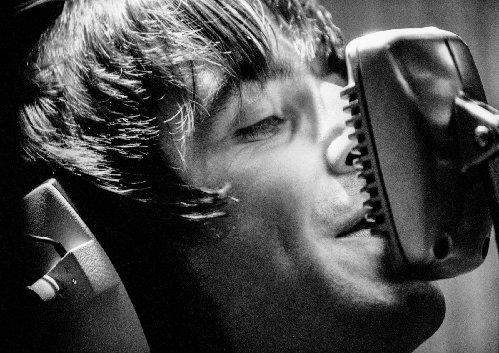 A limited edition print of Liam Gallagher at a microphone with headphones on in Olympic Studios.