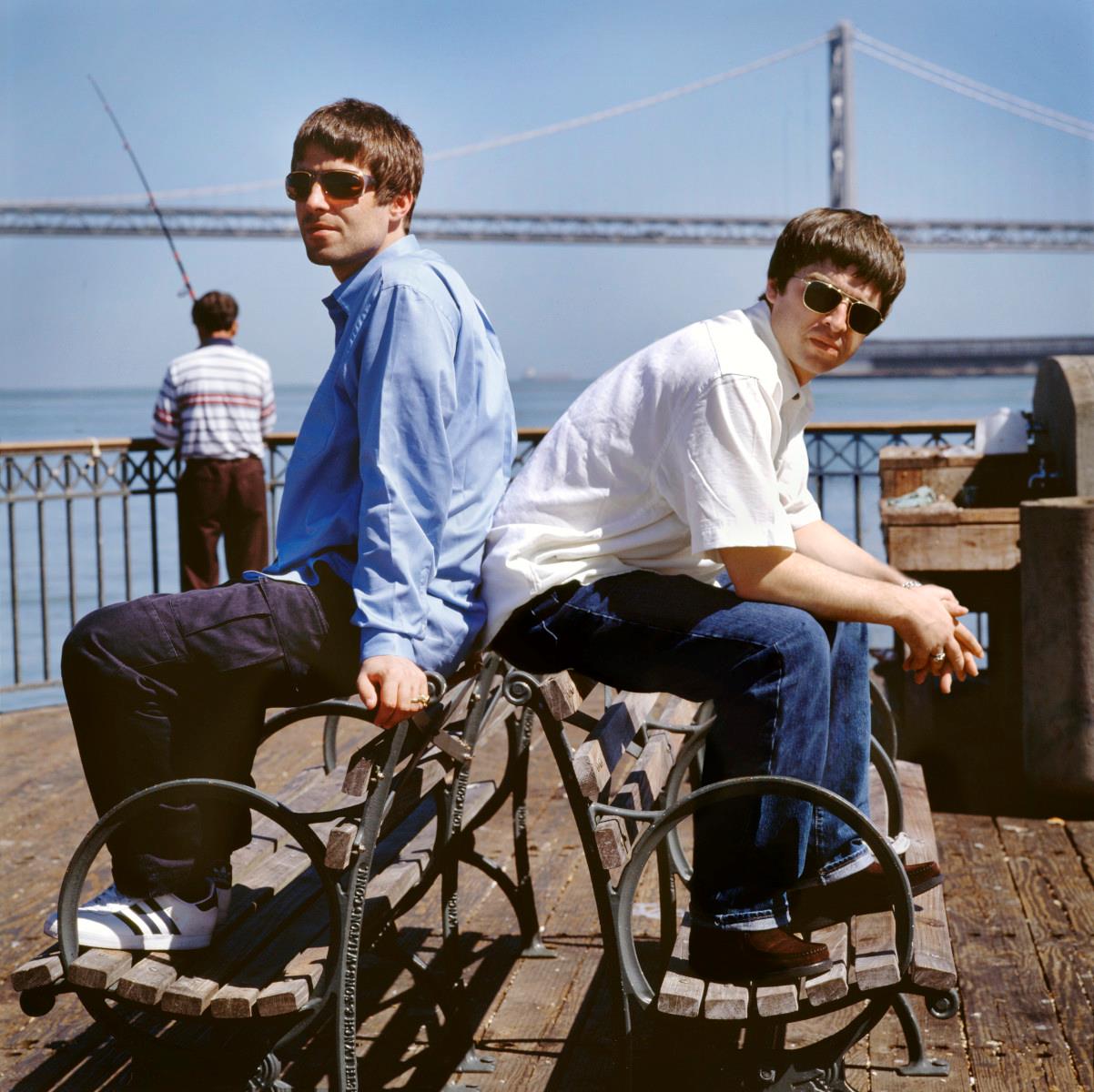 A limited edition colour print of Liam and Noel Gallagher sitting on benches back to back whilst looking at the camera in San Francisco in 2007.